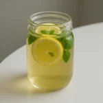 Homemade lemon balm recipe in a glass jar with mint and lemon on a wooden table