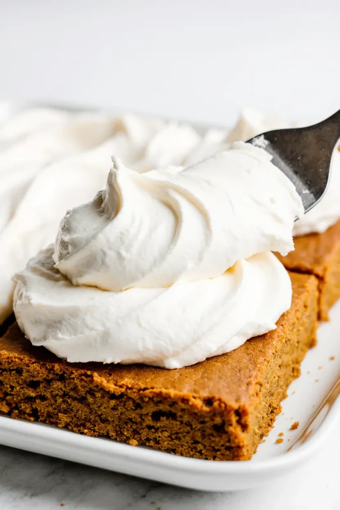 Frosting-Soft-Pumpkin-Bars Spreading thick cream cheese frosting over soft pumpkin bars with an offset spatula.