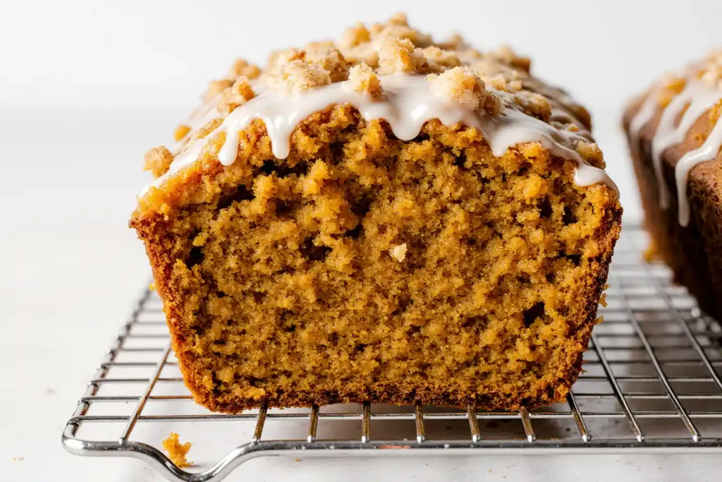 pumpkin streusel bread with golden crumbly topping and glaze drizzle, showing moist orange interior