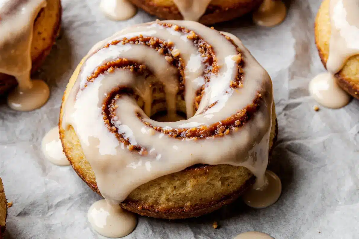 A close-up of a single, perfect Cinnamon Roll Cake Donut with cream cheese glaze.
