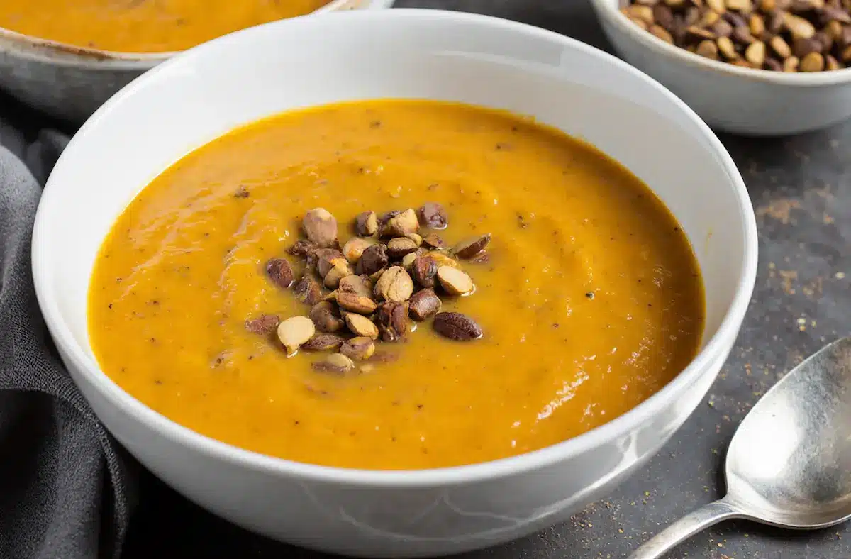 A bowl of easy pumpkin soup, creamy and garnished with pepitas.