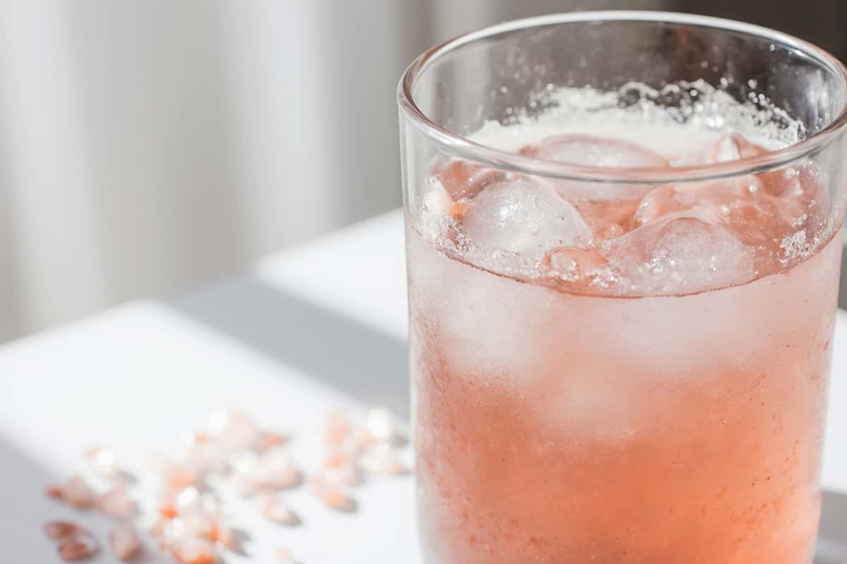 Pink salt and apple cider vinegar drink in a clear glass with morning sunlight