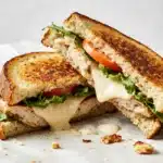 A Toasted Chicken Frontega sandwich cut in half to show the melted cheese and layers.