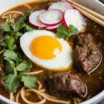 delicious bowl from a birria ramen recipe, with tender beef, a soft-boiled egg, and fresh toppings.