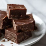 Easy 3 ingredient fudge recipe with chocolate chips and condensed milk stacked on white plate