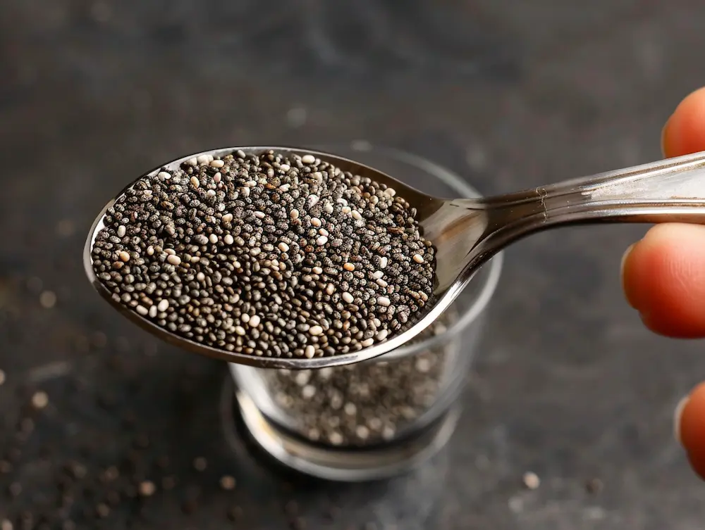 measuring 2 tablespoons chia seeds with measuring spoon for tadpole water recipe weight loss drink preparation