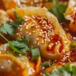 Viral dumpling bake recipe with frozen dumplings in creamy coconut curry sauce topped with chili crisp and fresh herbs