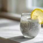 Natural Saxenda drink in a clear glass with chia seeds and lemon on a white counter.