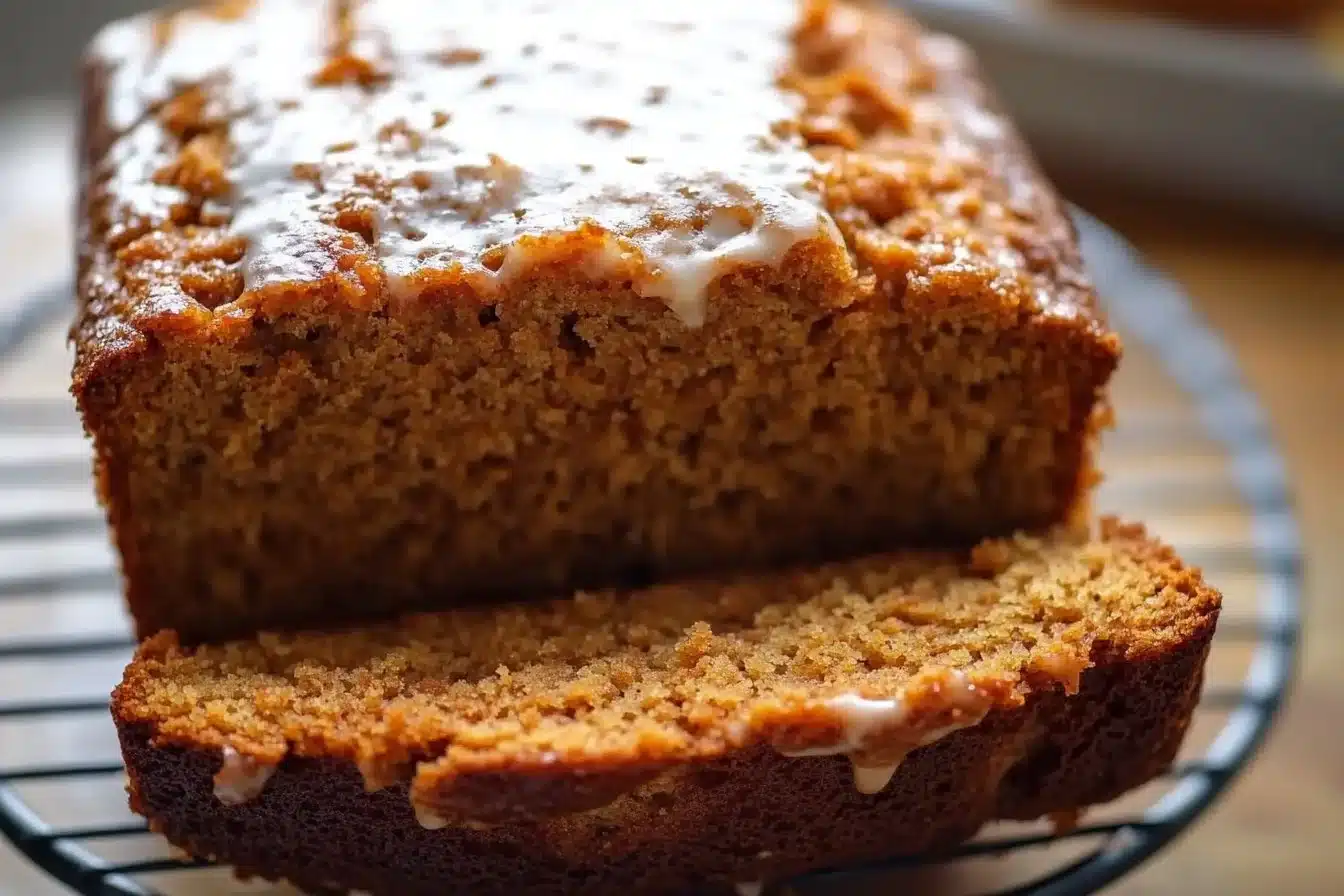 Sliced carrot cake loaf with cream cheese frosting on a wooden table