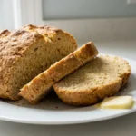 Sliced Irish soda bread loaf on a white plate with butter.
