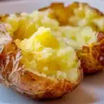 Jacket Potato Recipe: Crispy British Baked Potatoes Guide 3 Close-up of a crispy jacket potato split open with fluffy centre and butter on a white plate.