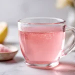 Pink Jillian Michaels gelatin weight loss drink in a clear glass mug on white marble