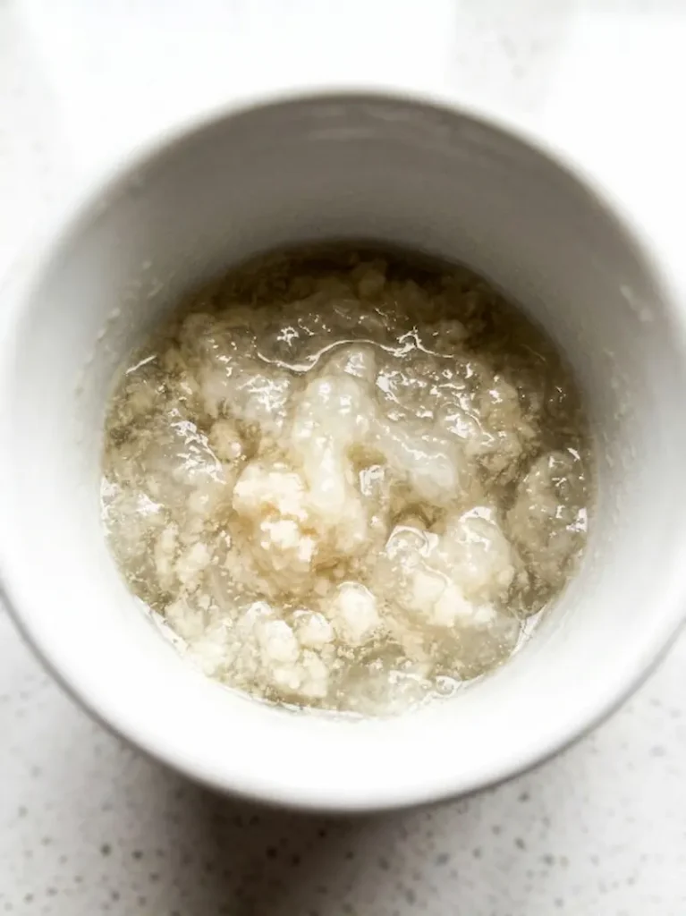 blooming unflavored gelatin powder in cold water in white mug
